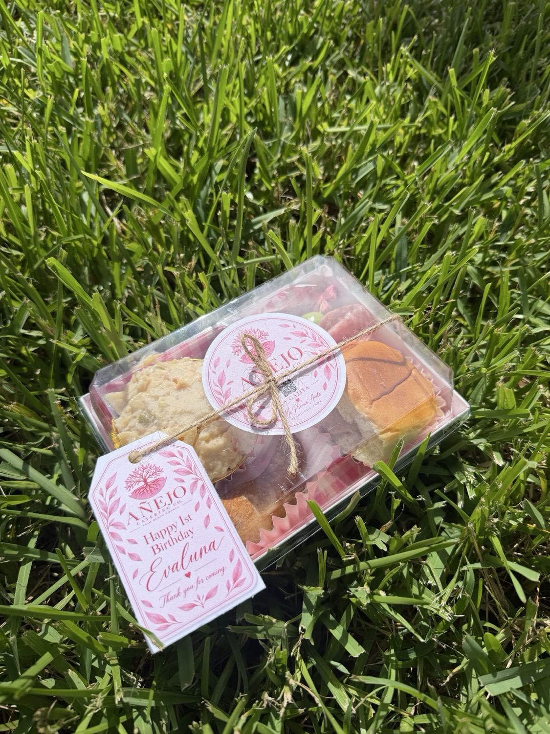 Close outdoor view of a personalized pink first-birthday Cajita